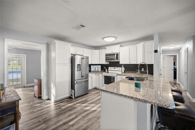 kitchen with decorative backsplash, white cabinetry, sink, and appliances with stainless steel finishes