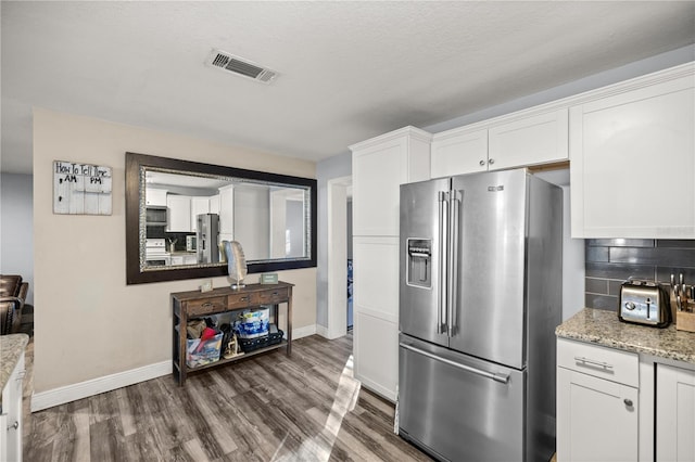 kitchen featuring white cabinets, appliances with stainless steel finishes, backsplash, and light stone countertops