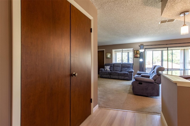 hall featuring a textured ceiling and light hardwood / wood-style flooring