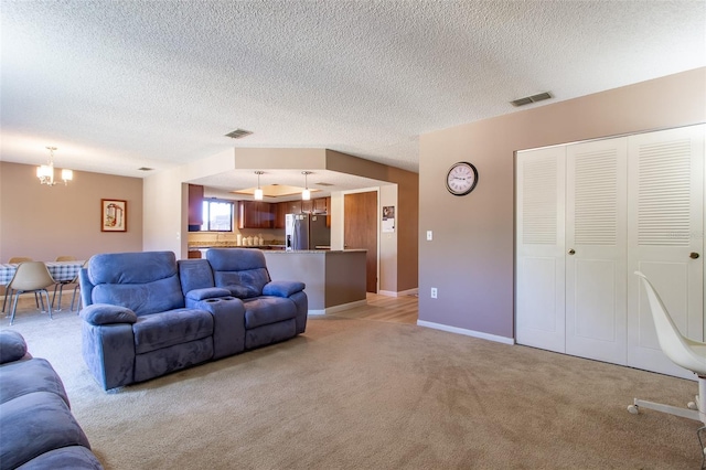 carpeted living room featuring a textured ceiling and an inviting chandelier