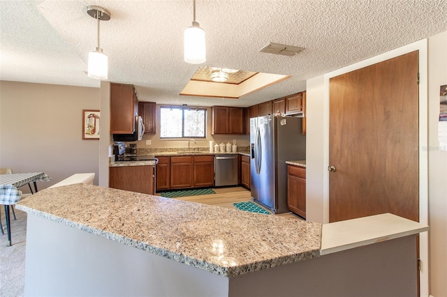 kitchen featuring kitchen peninsula, appliances with stainless steel finishes, a textured ceiling, sink, and hanging light fixtures