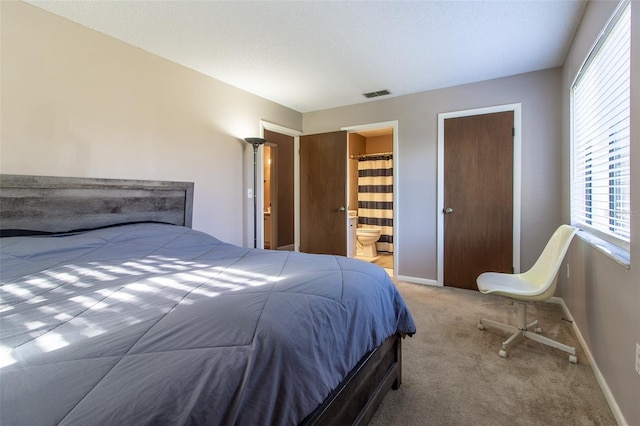 carpeted bedroom featuring ensuite bathroom and multiple windows