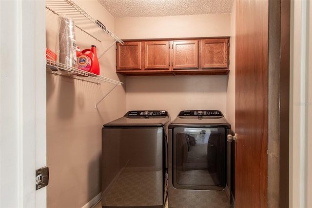 washroom with washer and dryer, a textured ceiling, and cabinets