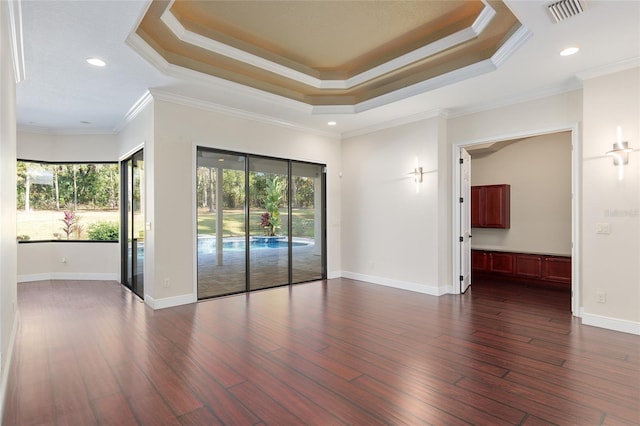 unfurnished room with a tray ceiling, dark hardwood / wood-style floors, and ornamental molding