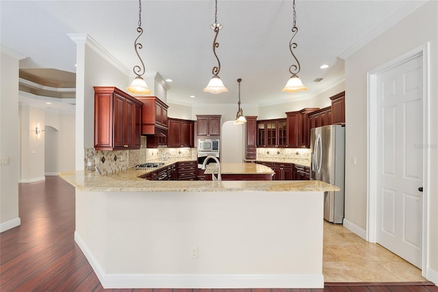 kitchen featuring backsplash, kitchen peninsula, crown molding, hanging light fixtures, and stainless steel appliances