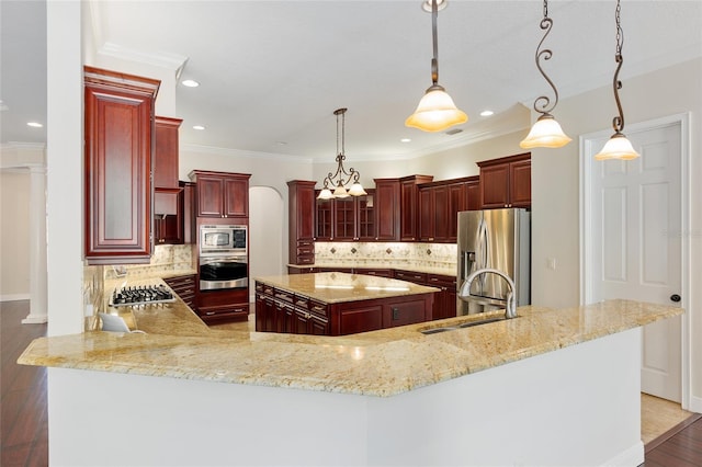 kitchen with a center island, stainless steel appliances, sink, hanging light fixtures, and backsplash