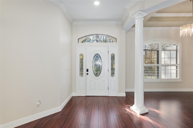 foyer featuring ornate columns, dark hardwood / wood-style floors, crown molding, and a notable chandelier