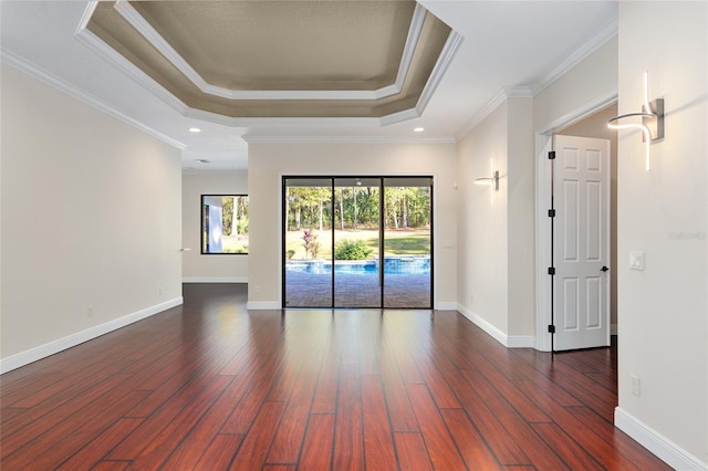 unfurnished room featuring dark wood-type flooring, ornamental molding, and a raised ceiling