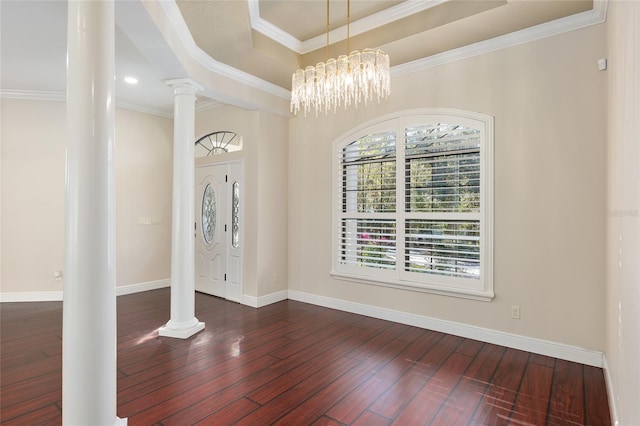 entryway featuring dark wood-type flooring, a chandelier, ornamental molding, and a raised ceiling