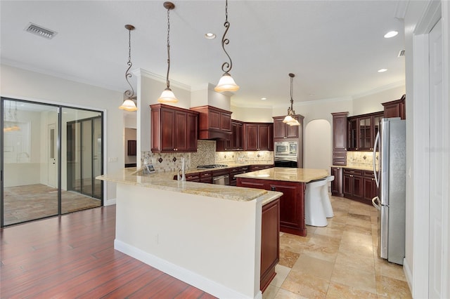 kitchen with tasteful backsplash, appliances with stainless steel finishes, kitchen peninsula, and a kitchen island