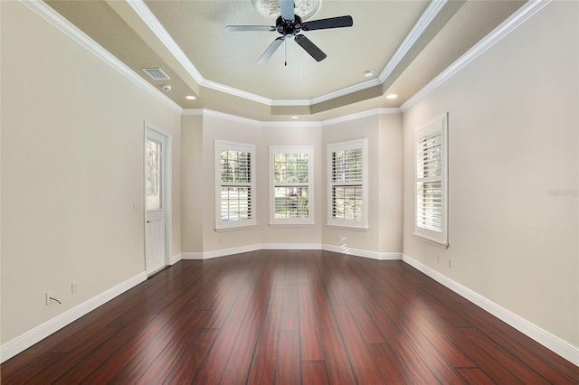 empty room featuring a raised ceiling, ceiling fan, dark hardwood / wood-style floors, and ornamental molding