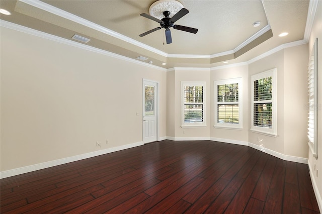 unfurnished room with ceiling fan, a tray ceiling, dark hardwood / wood-style floors, and crown molding