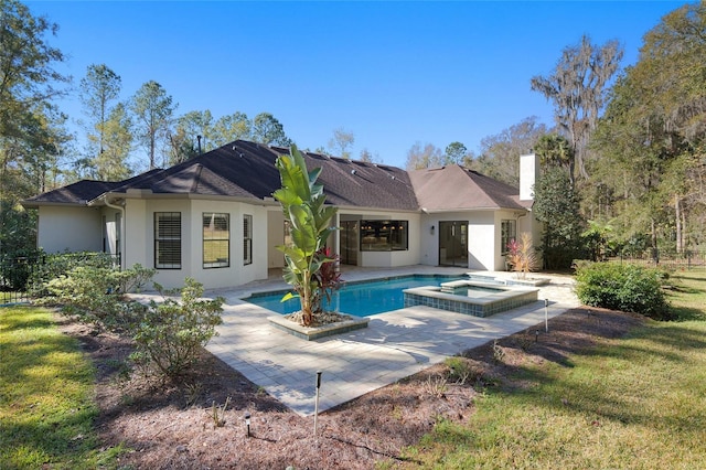 back of property with a lawn, a swimming pool with hot tub, and a patio