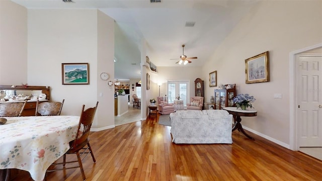 living room with light hardwood / wood-style floors, ceiling fan, french doors, and lofted ceiling