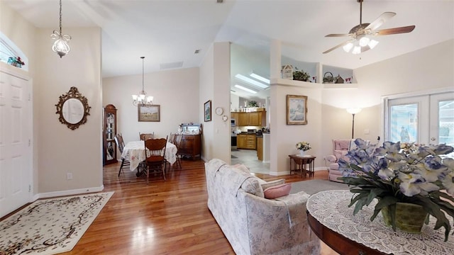 living room with ceiling fan with notable chandelier, lofted ceiling, hardwood / wood-style floors, and a healthy amount of sunlight