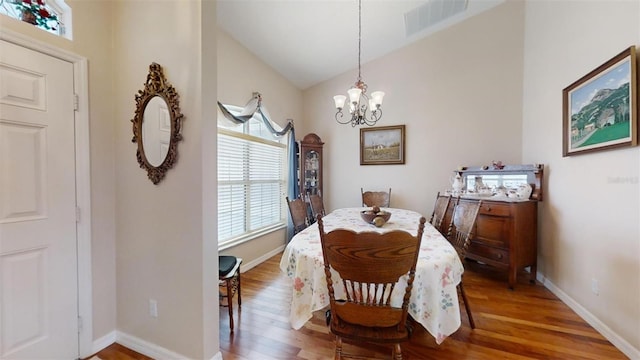 dining space featuring a notable chandelier, lofted ceiling, and hardwood / wood-style flooring