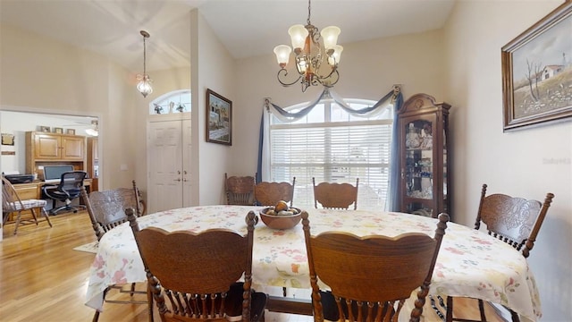 dining space with light hardwood / wood-style flooring, an inviting chandelier, and lofted ceiling