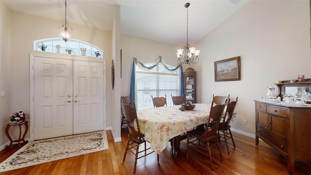 dining room featuring wood-type flooring, vaulted ceiling, and a notable chandelier