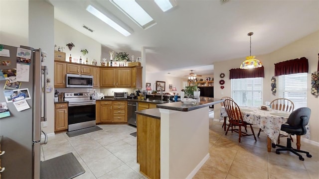 kitchen featuring appliances with stainless steel finishes, pendant lighting, kitchen peninsula, and light tile patterned floors