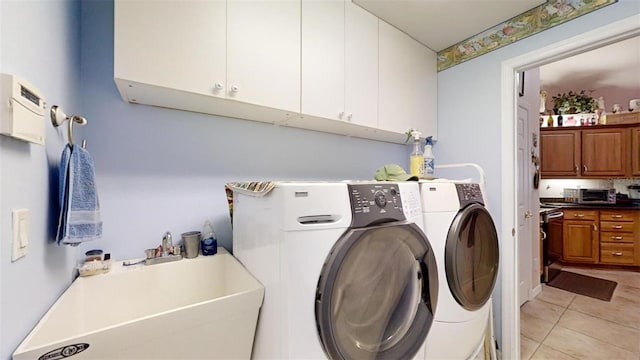 clothes washing area featuring washing machine and dryer, cabinets, light tile patterned floors, and sink