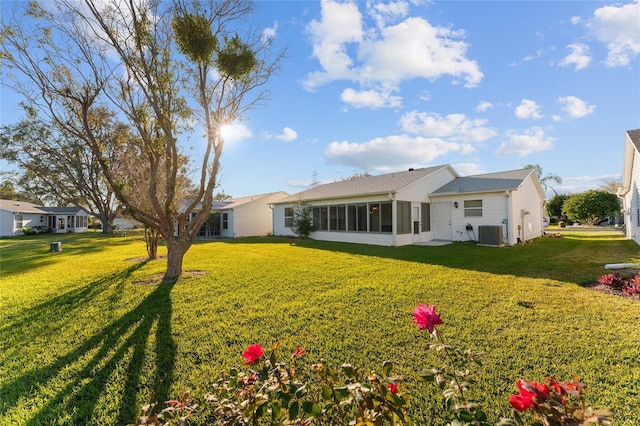 rear view of house featuring cooling unit, a lawn, and a sunroom