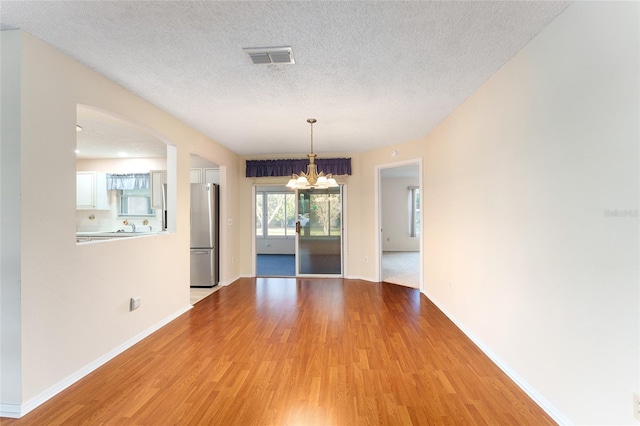 unfurnished dining area with a chandelier, hardwood / wood-style floors, and a textured ceiling