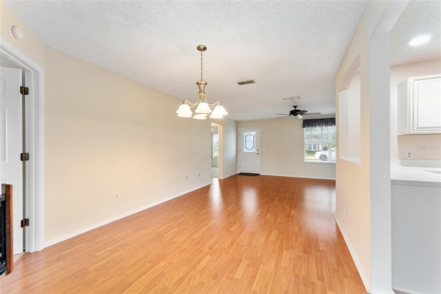 unfurnished living room with light hardwood / wood-style flooring, ceiling fan with notable chandelier, and a textured ceiling