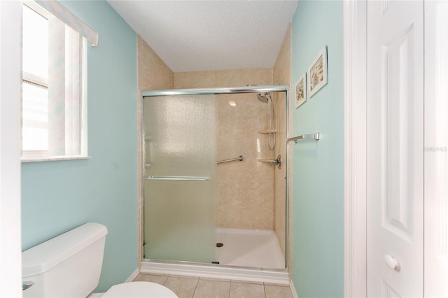 bathroom featuring tile patterned floors, toilet, a textured ceiling, and walk in shower