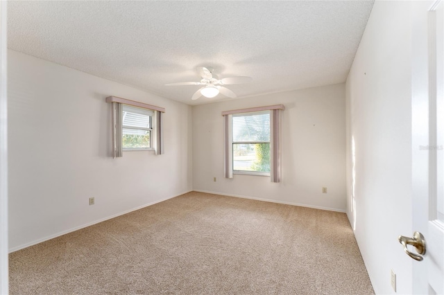 carpeted empty room featuring a textured ceiling, plenty of natural light, and ceiling fan