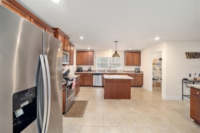 kitchen with stainless steel appliances, light tile patterned floors, light stone counters, a kitchen island, and decorative light fixtures