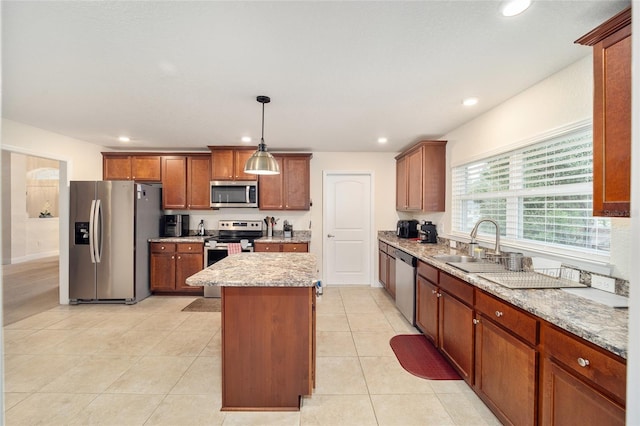 kitchen featuring sink, light stone countertops, a kitchen island, pendant lighting, and appliances with stainless steel finishes