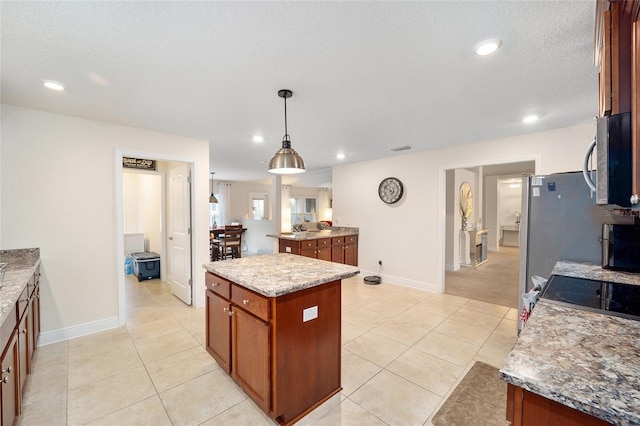 kitchen with a kitchen island, light tile patterned flooring, hanging light fixtures, and light stone countertops