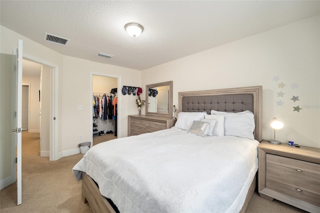 carpeted bedroom with a walk in closet, a closet, and a textured ceiling