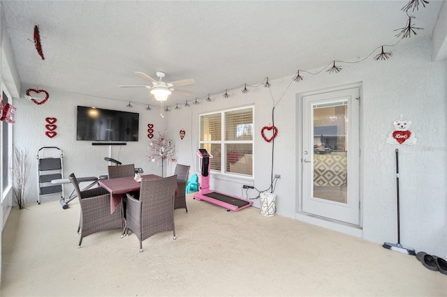 carpeted dining area with a textured ceiling and ceiling fan