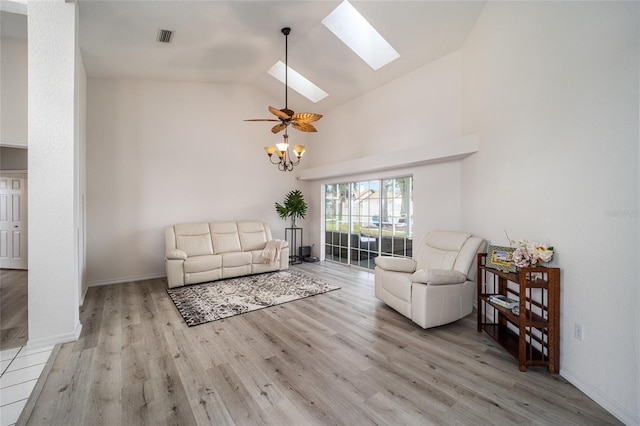 living room with vaulted ceiling with skylight, ceiling fan, and light wood-type flooring