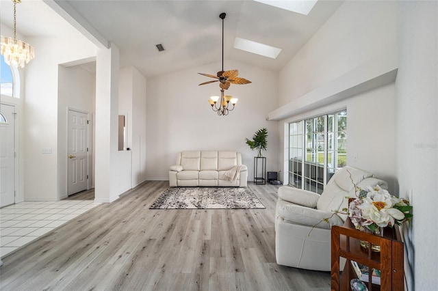 living room featuring ceiling fan with notable chandelier, light wood-type flooring, high vaulted ceiling, and a skylight