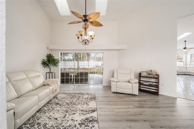 living room with hardwood / wood-style flooring, a notable chandelier, and a skylight