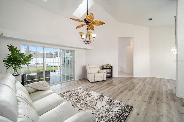 living room with ceiling fan, light hardwood / wood-style floors, and lofted ceiling with skylight