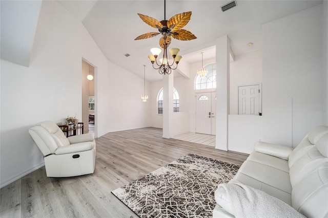 living room with ceiling fan with notable chandelier, light wood-type flooring, and high vaulted ceiling