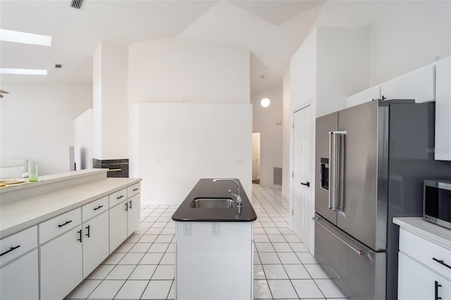 kitchen with sink, stainless steel appliances, light tile patterned floors, an island with sink, and white cabinets