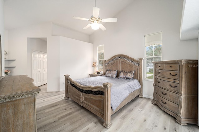 bedroom featuring ceiling fan, light hardwood / wood-style flooring, high vaulted ceiling, and a closet