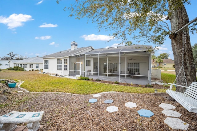 rear view of house with glass enclosure, a yard, and a patio