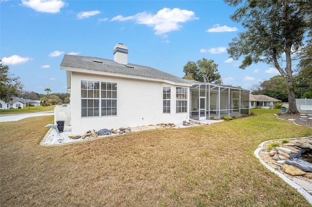 rear view of property featuring glass enclosure and a yard