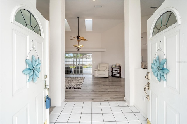 entrance foyer with visible vents, light tile patterned floors, baseboards, and vaulted ceiling