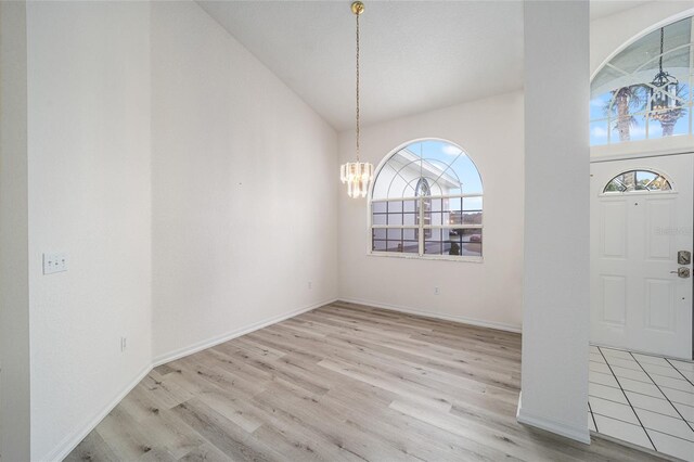 entrance foyer featuring high vaulted ceiling, baseboards, an inviting chandelier, and wood finished floors