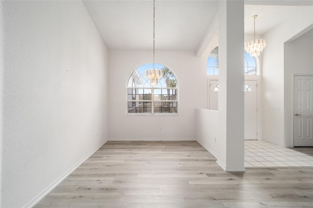 unfurnished dining area with a chandelier, baseboards, and wood finished floors