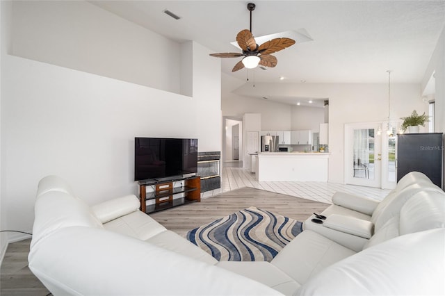 living area with light wood-type flooring, high vaulted ceiling, ceiling fan, and visible vents