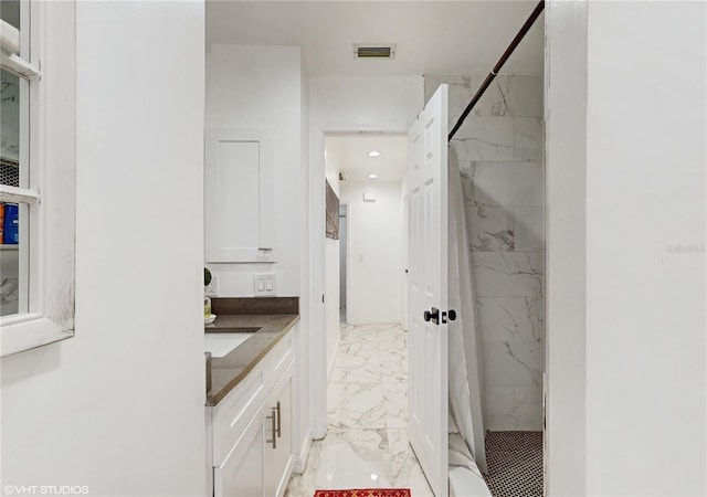 bathroom with vanity and tiled shower