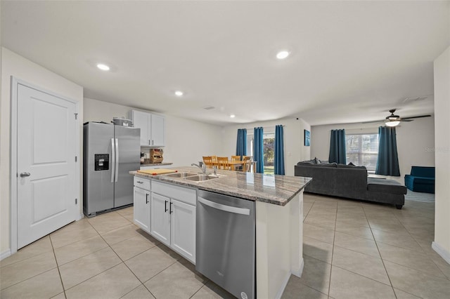 kitchen featuring light stone countertops, stainless steel appliances, ceiling fan, white cabinetry, and an island with sink