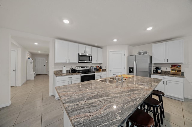 kitchen featuring appliances with stainless steel finishes, sink, white cabinetry, and an island with sink